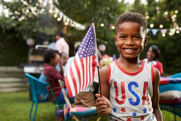 Glückliches Kind, das die amerikanische Flagge schwenkt